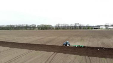 Havacılık. Bahar güneşli bir gün. Tarımsal bir tarlada traktör toprak, toprak ve modern tarım sürüyor. Eko çiftliği.