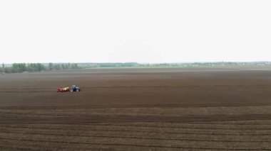 Havacılık. Bahar güneşli bir gün. Tarım alanında, özel ekipmanlı bir traktör patates ekiyor. Çiftliklerde otomatik patates ekimi. modern tarım.