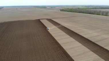 Havacılık. Bahar güneşli bir gün. Tarımsal bir tarlada traktör toprak ve toprak sürüyor. Çiftliklerde otomatik patates ekimi. Modern tarım. Eko çiftliği.