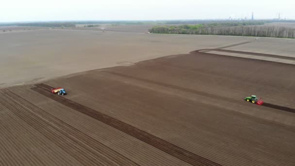 Аеро. Сільськогосподарське поле, трактори зі спеціальним обладнанням ораторського ґрунту, саджають картоплю. Автоматизоване саджання картоплі на фермах. Сучасне сільське господарство. Сонячний день. — стокове відео
