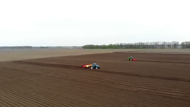 Аеро. Сільськогосподарське поле, трактори зі спеціальним обладнанням ораторського ґрунту, саджають картоплю. Автоматизоване саджання картоплі на фермах. Сучасне сільське господарство. Сонячний день. — стокове відео