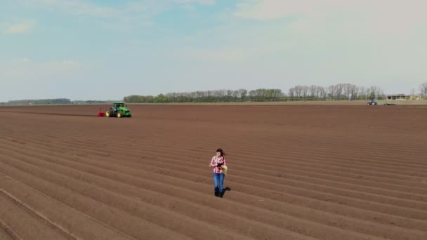 Aero. agricultora, agrónoma está en el campo con hileras especiales de suelo. Ella prueba, usando tableta, la calidad de la plantación automatizada de patata por tractores. Agricultura moderna, agricultura. Primavera día soleado . — Vídeos de Stock