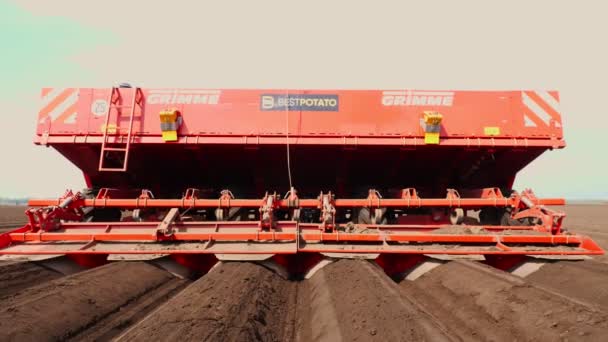 Primo piano, il coltivatore pianta automaticamente patate in file di terreno diritte in campo agricolo, aggiunge fertilizzanti minerali al terreno, per una migliore crescita delle patate. agricoltura moderna. primavera giornata di sole — Video Stock