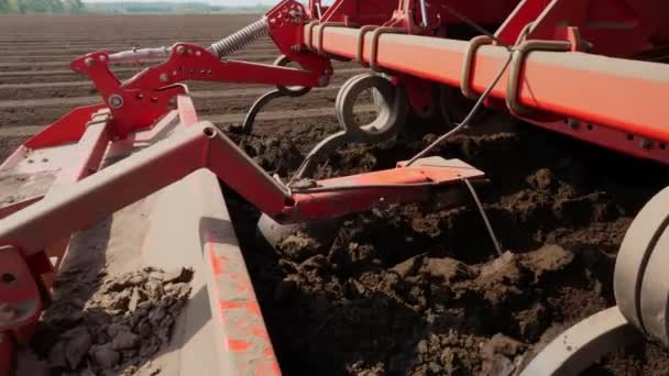 Close-up, cultivator automatically plants potatoes in straight soil rows in farm field, adds mineral fertilizers to soil, for better potato growth. modern agriculture. spring sunny day — Stock Video