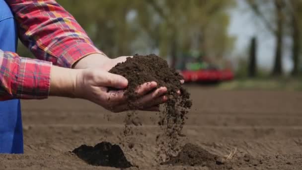 Close-up de mão, agricultor, agrônomo verifica a qualidade do solo no campo da fazenda. fundo de trabalho trator, cultivador. Cultivo de batata agrícola moderna. primavera dia ensolarado . — Vídeo de Stock