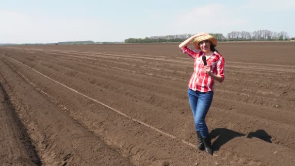 Vrouwelijke journaliste vertelt voor TV nieuwsbericht over Moderne teelt. geploegde agrarische veld achtergrond. planttijd of oogst. warme zonnige dag — Stockvideo