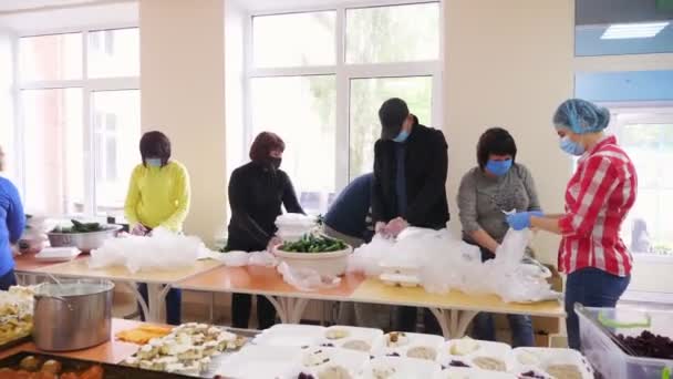 CHERKASY, UKRAINE, MUNGKIN 18, 2020: Relawan berkemas Lunchbox, makanan gratis untuk disampaikan kepada orang miskin dan tunawisma selama penguncian covid19. Proyek amal, menyumbangkan bantuan, pengiriman makanan — Stok Video