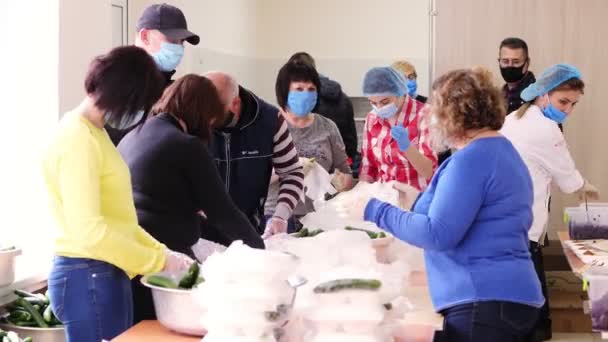 CHERKASY, UKRAINE, 18 de maio de 2020: voluntários embrulhar lancheiras com refeições de caridade em sacos de plástico, adicionar pepinos. entrega gratuita de alimentos para pessoas pobres durante covid19. Projecto de caridade, doação de ajuda — Vídeo de Stock