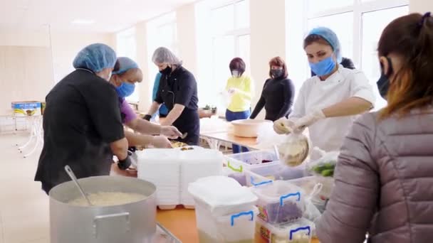 CHERKASY, UKRAINE, 18 de maio de 2020: Voluntários embalam refeições quentes gratuitas em lancheiras, para serem entregues a pessoas pobres e desabrigadas durante o fechamento do covid19. Projecto de caridade, doação de ajuda, entrega de alimentos — Vídeo de Stock