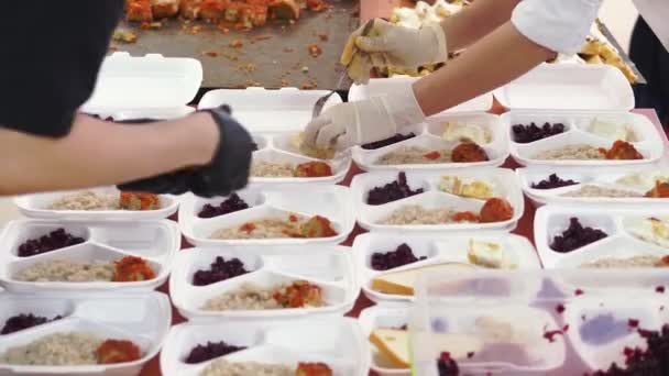 Nahaufnahme: Freiwillige packen kostenlose warme Mahlzeiten in Lunchboxen für arme Menschen während der Covid19. Essensausgabe. Wohltätigkeitsprojekt, Hilfe spenden, — Stockvideo