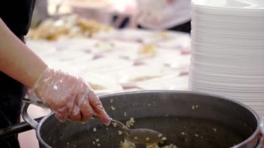 Yakın plan, kadın gönüllü lapayı büyük tavadan yemek kutusuna koyar. Yoksul ve evsizler için sıcak yemek. Bedava yemek servisi. bağış yardımı,