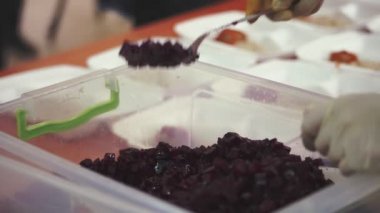 Yakın plan, tek kullanımlık eldivenler. Yemek kutusundan salata koy. Gönüllüler tarafından 19. yılda fakirlere ücretsiz sıcak yemek dağıtılıyor. Yemek servisi..