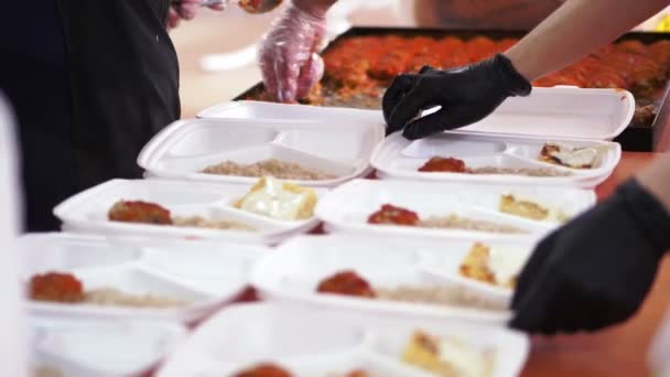 Close-up, mains dans les gants jetables emballent des repas chauds de charité dans des boîtes à lunch, pour être livrés gratuitement aux pauvres par des bénévoles pendant le confinement de la covid19. livraison de nourriture . — Video
