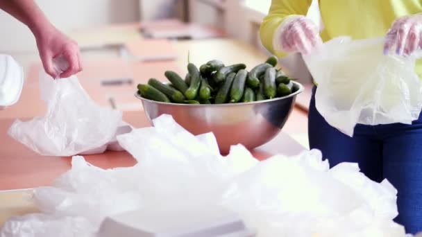 Zbliżenie, ręce. wolontariusze owijają pojemniki na pianę posiłkami charytatywnymi w plastikowe torebki i dodają ogórki. bezpłatna dostawa żywności dla ubogich w trakcie planowania19. Projekt charytatywny, dotacja — Wideo stockowe