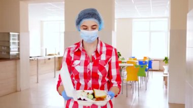 Maskeli ve eldivenli kadın gönüllü, zavallı, evsiz insanlar için sıcak, köpüklü bir beslenme çantası tutuyor. Bedava yemek servisi. bağış yardımı,