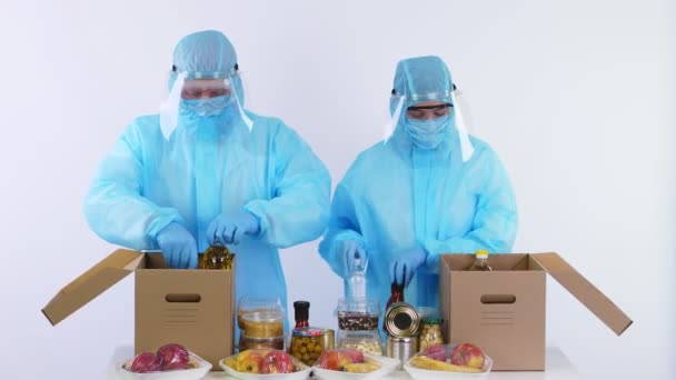 Voluntarios en guantes de protección, trajes de paquete de comestibles a cajas de cartón Donación. Despegue, servicio de entrega de comida a domicilio, durante coronavirus. Compras en línea. Caridad . — Vídeos de Stock