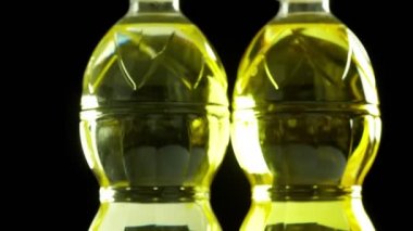 Yakın plan, rafine edilmemiş sebze ayçiçeği veya plastik şişelerdeki mısır yağı, yiyecek ürünleri siyah arka planda dönüyor. İnternetten alışveriş. Yemek servisi.,