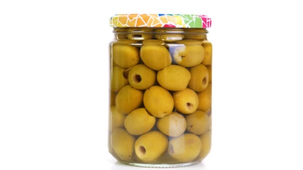 Primer plano, aceitunas verdes grandes en escabeche en un frasco de vidrio, producto alimenticio girar sobre fondo blanco. compras en línea de comestibles. comida a domicilio, conservación de alimentos — Vídeos de Stock