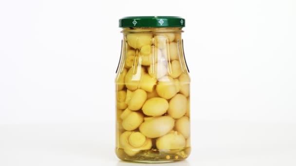 Primer plano, champiñones en escabeche champiñones en un frasco de vidrio, producto alimenticio girar sobre fondo blanco. compras en línea de comestibles. comida a domicilio. conservación de alimentos — Vídeos de Stock