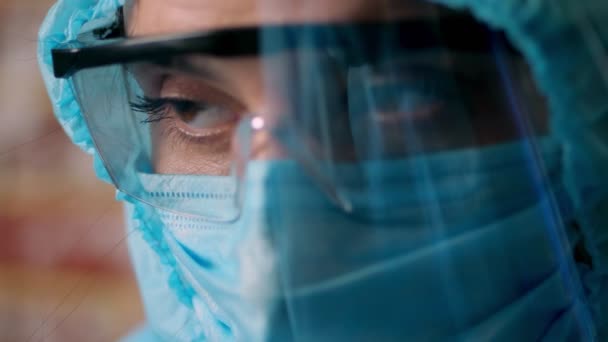 Portret van een vrouwelijke arts in een speciaal beschermend pak, masker, bril en een beschermscherm. vermoeide en uitgeputte dokter. Coronavirusepidemie — Stockvideo