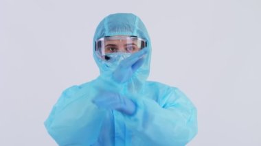 Kadın doktor ya da hemşire, koruyucu üniformalı, maske, eldiven, gözlük takan, kameraya bakan, el hareketlerini gösteren. Koronavirüs salgını. Beyaz arka plan. Coronavirus koruması