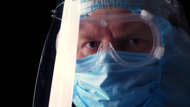 Portret van een mannelijke arts. Uitgeputte en vermoeide arts die coronavirus beschermend uniform, masker, bril en beschermscherm afdoet. een pandemische covid-19 — Stockvideo