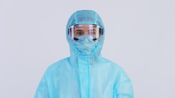 Özel koruyucu üniformalı, maskeli, gözlüklü kadın doktor ya da hemşire portresi. Koronavirüs salgını. Beyaz arka planda. Coronavirus koruması — Stok video