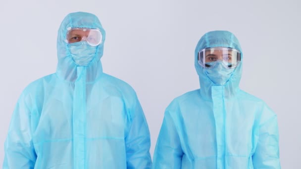 Trabajadores médicos, médicos y enfermeras, con uniformes protectores especiales, máscaras, gafas, mirando a la cámara. epidemia de coronavirus. sobre fondo blanco. protección contra el coronavirus — Vídeos de Stock