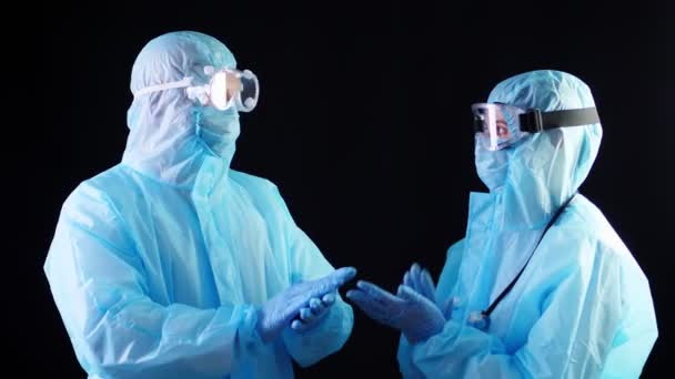 Dos trabajadores médicos, médico o enfermero, en trajes de protección especiales, máscaras, gafas están aplaudiendo. Brote de Covid-19. protección contra el coronavirus — Vídeos de Stock