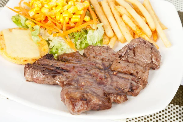 Carne grelhada com batatas fritas e salada — Fotografia de Stock