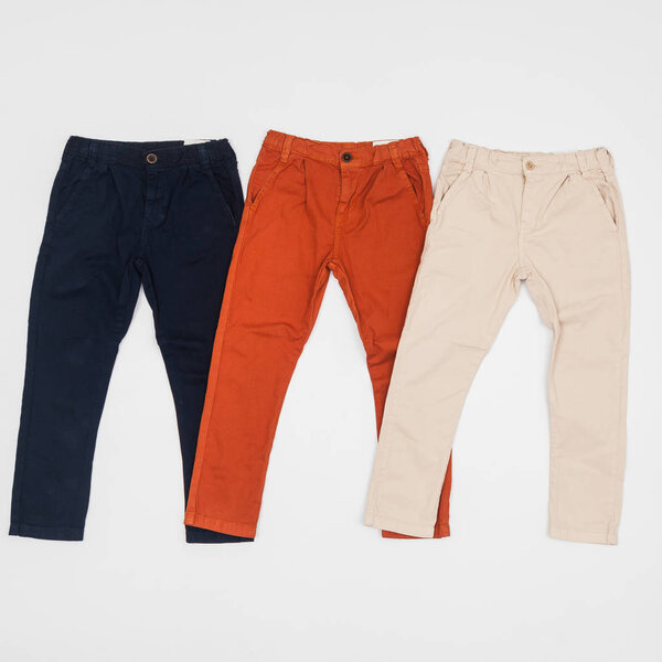 fashion - three pants of different color for children, photo on neutral background.