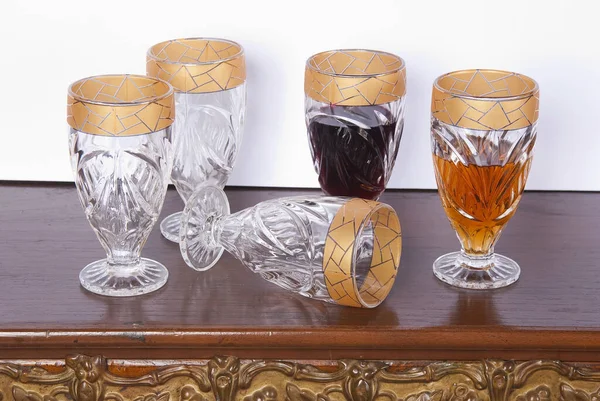 drink, set of five gold rimmed glass goblets; photo on wooden background.