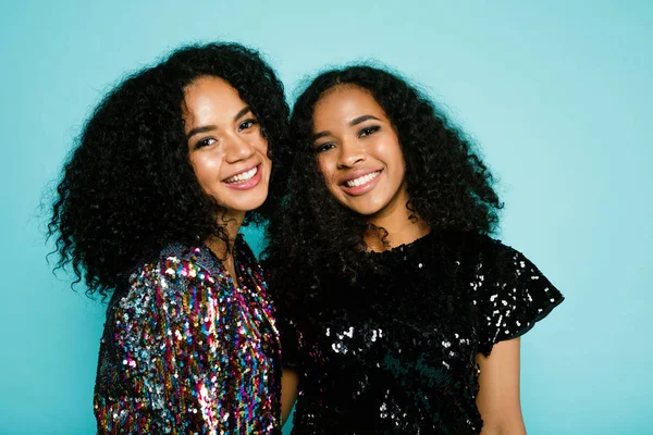 Smiling friends standing at blue background in studio