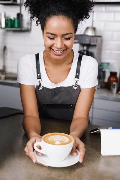 Happy waitress looking at cup of coffee