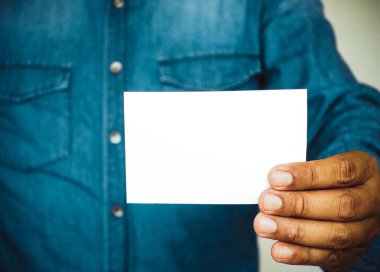 Beton duvar arka plan üzerinde beyaz kartvizit tutan adam