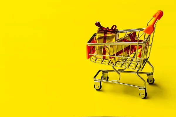 黄色い背景のショッピングカートのおもちゃ. — ストック写真