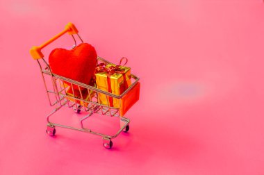 Pembe bir sırt üzerinde farklı renklerde hediyelerle dolu bir alışveriş arabası.