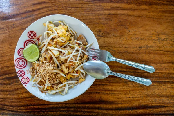 Thai style gebratene Nudeln in einem Teller auf einem Holztisch. — Stockfoto