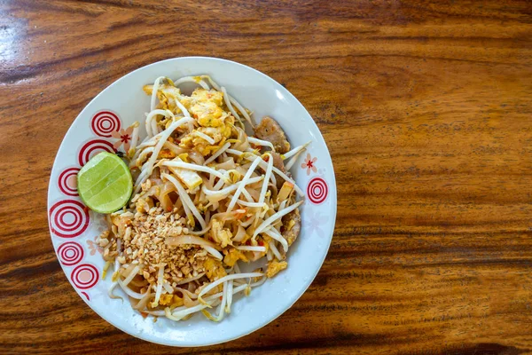 Thai stílusú sült tészta egy tányéron egy fa asztalon. — Stock Fotó