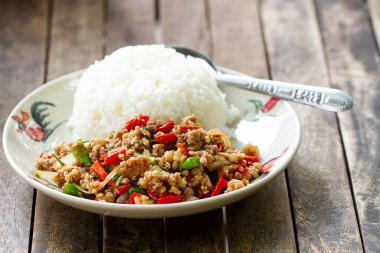 Üzerine kızarmış domuz eti ve fesleğenle birlikte beyaz bir tabakta pirinç. (Ön odak)