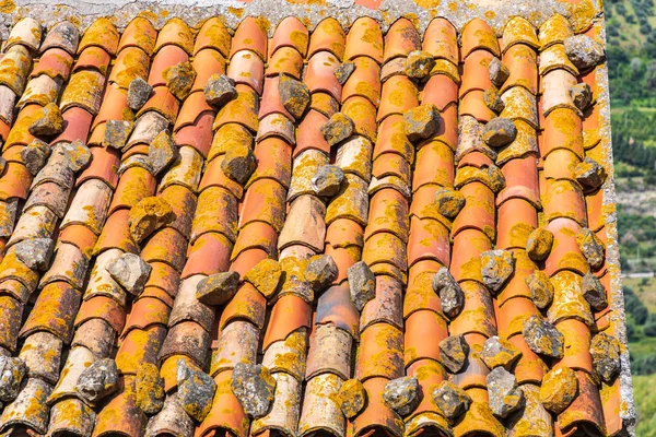 Italy, Sicily, Messina Province, Caronia. A terra cotta tile roof with stones in the medieval hilltop town of Caronia.