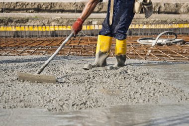 Beton döşeme sırasında inşaat alanında çalışan bir duvarcı bir evin temellerini inşa etmek için çalışıyor.