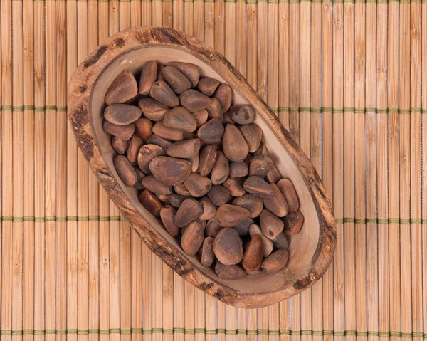 Органические кедровые орехи в раковине из оливкового дерева — стоковое фото