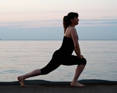 Güneş doğarken genç aktif kadın germe yapmak egzersizleri