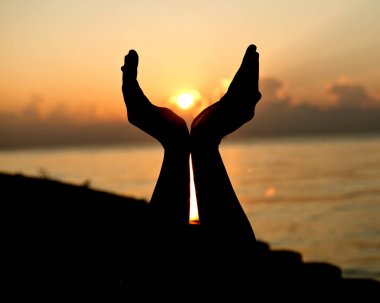 Siluet insan güneş üzerinde avuç içi kadar açık boş ellerle