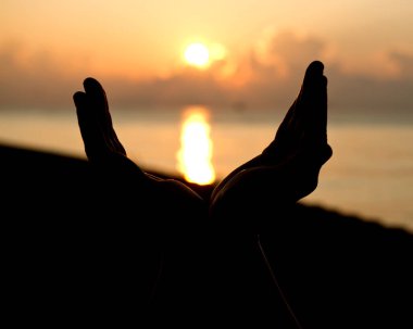 Siluet insan güneş üzerinde avuç içi kadar açık boş ellerle