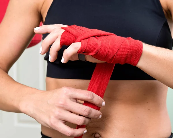 Młoda kobieta aktywna, przygotowanie do ćwiczeń jej ręce z czerwonym bandaż taśmy do pakowania — Zdjęcie stockowe