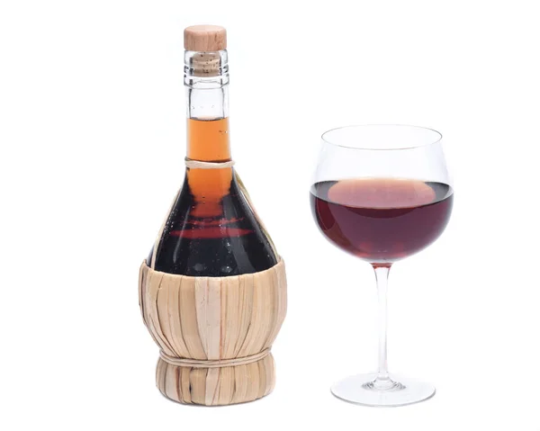 Красное гранатовое вино в стакане и бутылка соломенного вина — стоковое фото