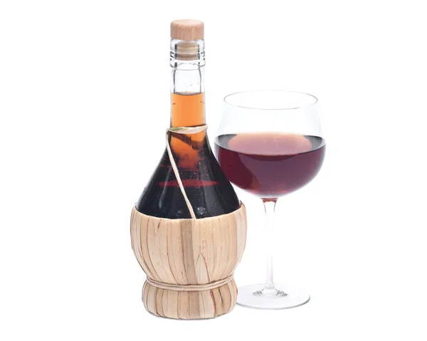 Красное гранатовое вино в стакане и бутылка соломенного вина — стоковое фото