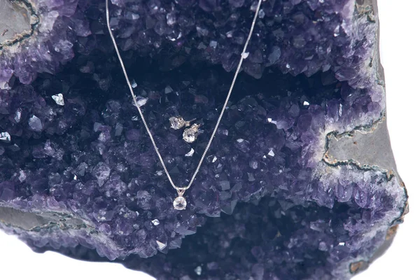 Kryształowe kolczyki i wisiorek srebrny łańcucha przedstawione na amethyst geode — Zdjęcie stockowe